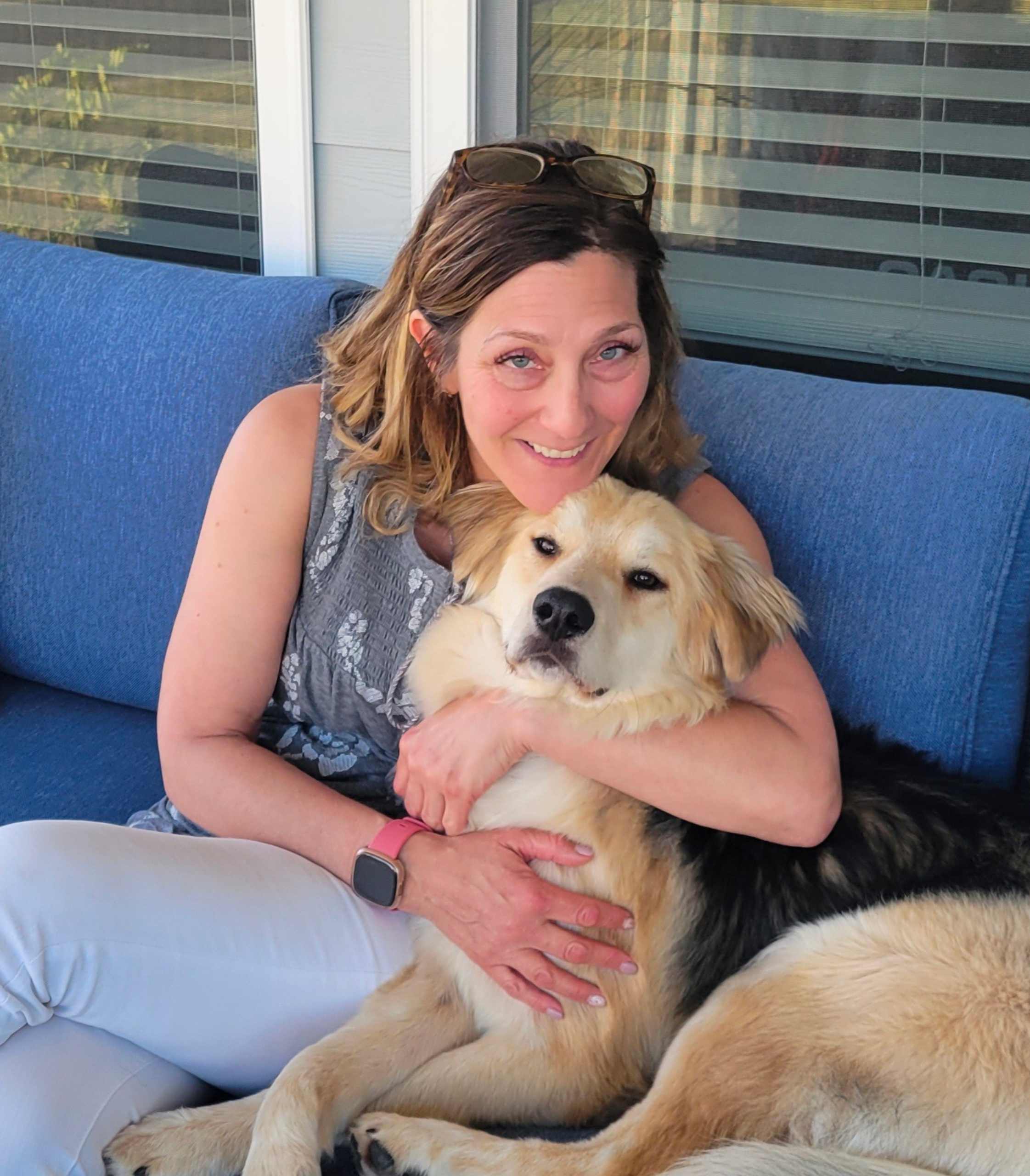 A woman sitting on the couch with her dog.