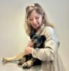 A woman holding onto a dog with its paw